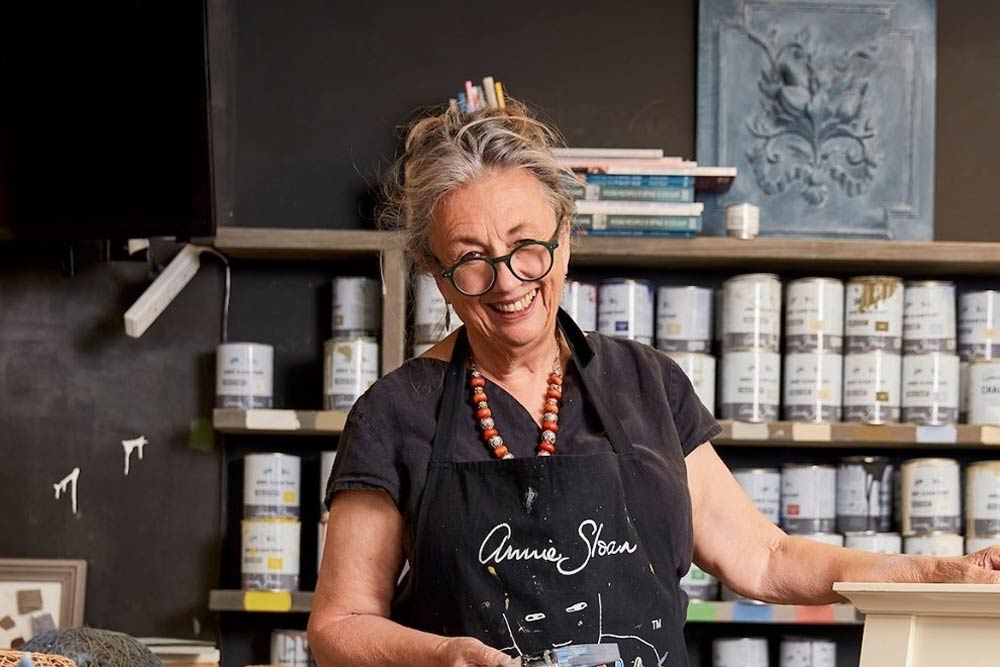 Photograph of Annie Sloan, renowned paint and fabric designer, surrounded by her vibrant creations.