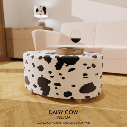 A contemporary oval coffee table footstool, with a bold and striking cow print pattern on Velboa fabric.